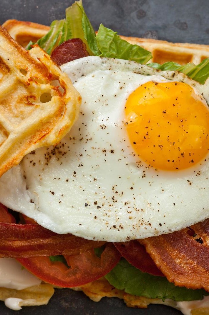 This savory cheddar waffle BLT sandwich features a savory Belgian waffle, topped with bacon, lettuce, tomato, and a gooey fried egg. | peteandgerrys.com 