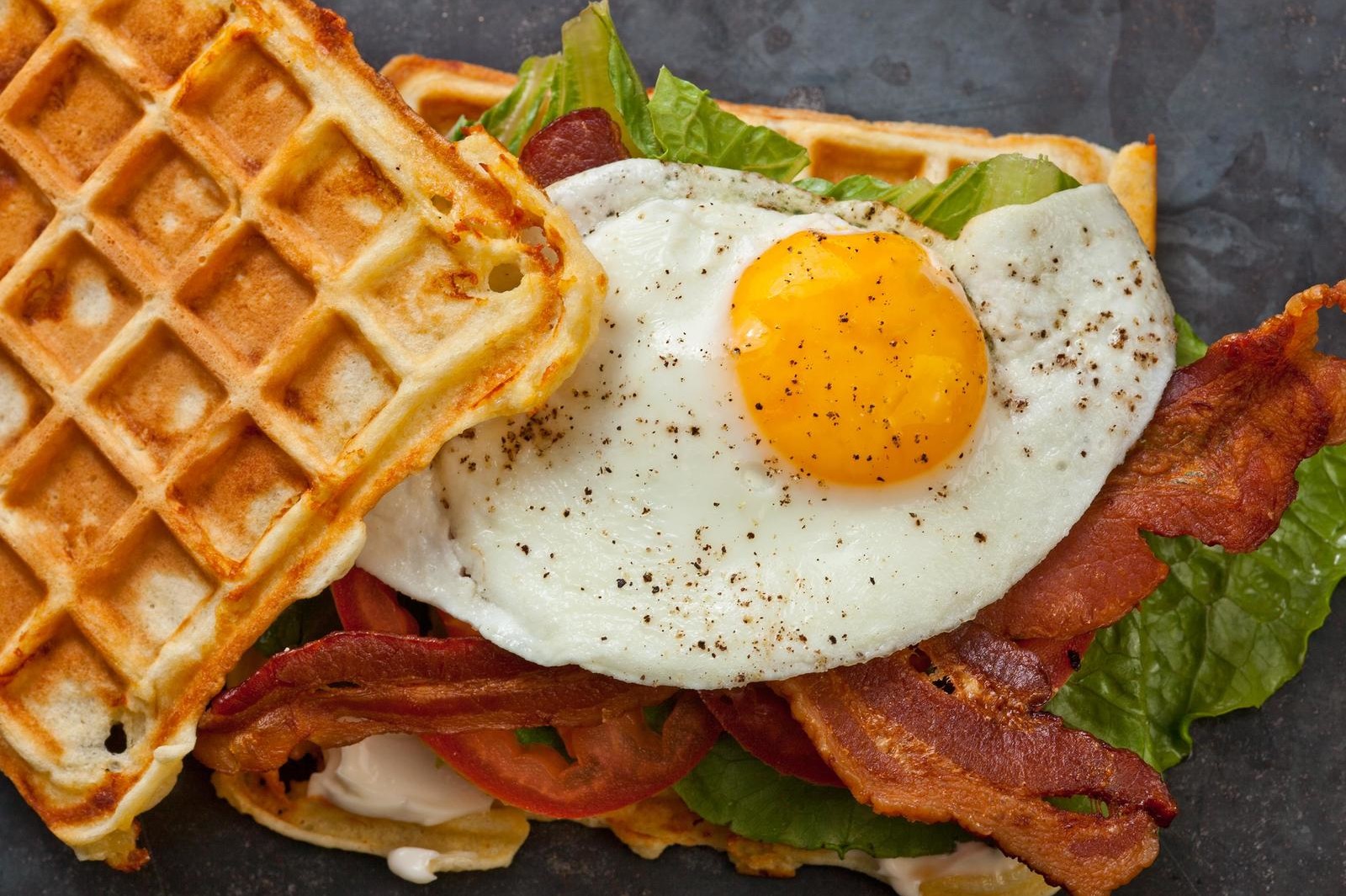 This savory cheddar waffle BLT sandwich features a savory Belgian waffle, topped with bacon, lettuce, tomato, and a gooey fried egg. | peteandgerrys.com 