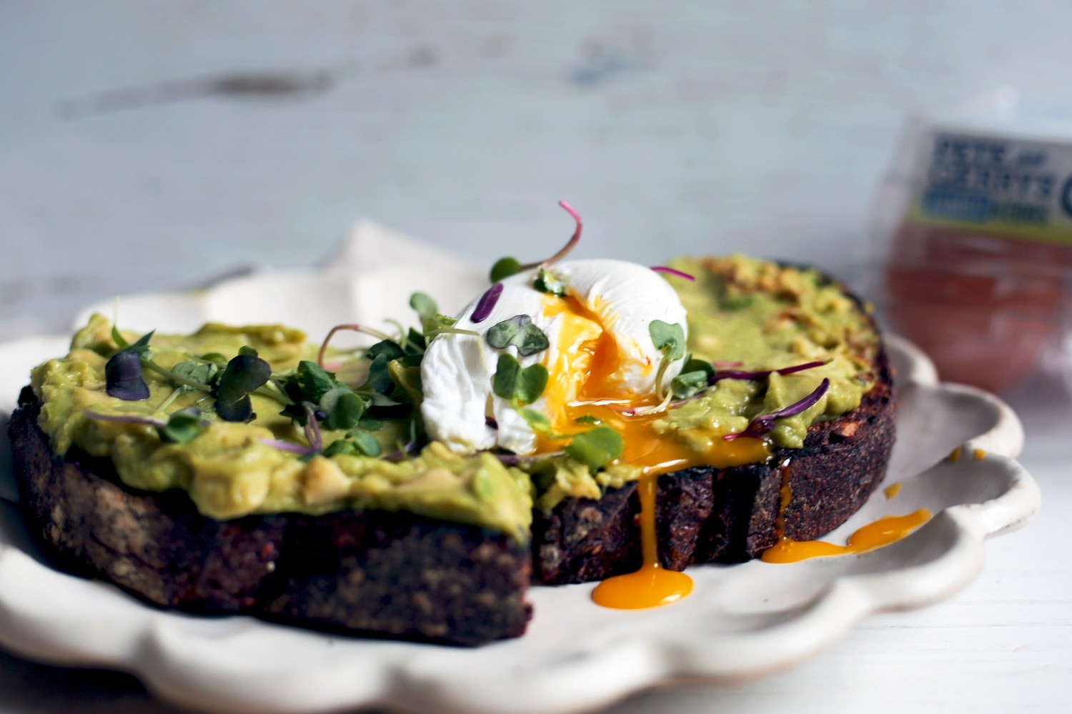 Toasted slice of sourdough bread topped with mashed avocado, microgreens, a runny poached organic egg, and a drizzle of CBD-infused coconut oil. | peteandgerrys.com 