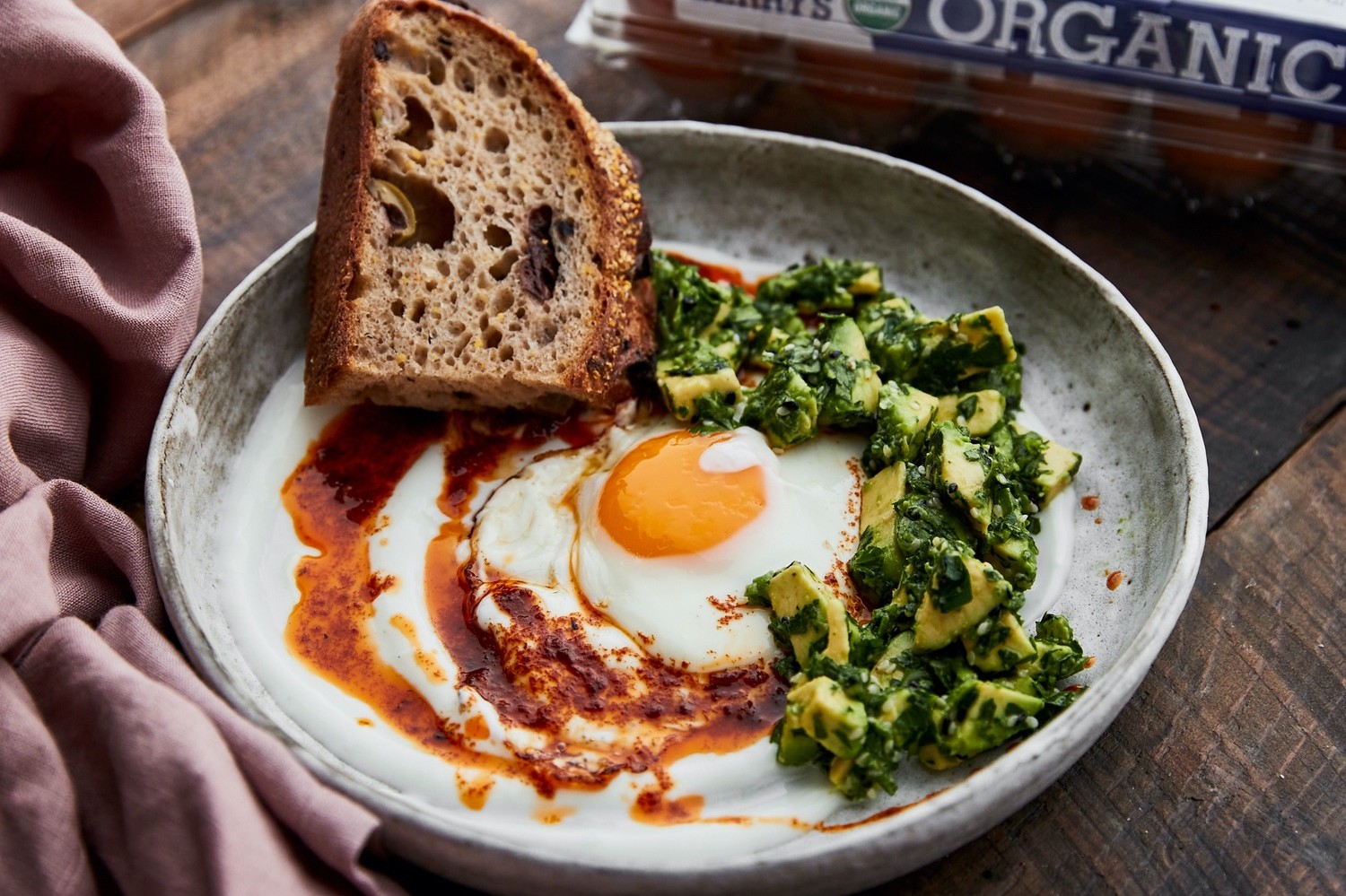 This Turkish eggs with harissa butter or "cilbir" is a great dish to add to the dinner lineup. Pictured is rustic bread served with a runny egg, a spoonful of avocado relish, and a drizzle of harissa butter. | peteandgerrys.com 