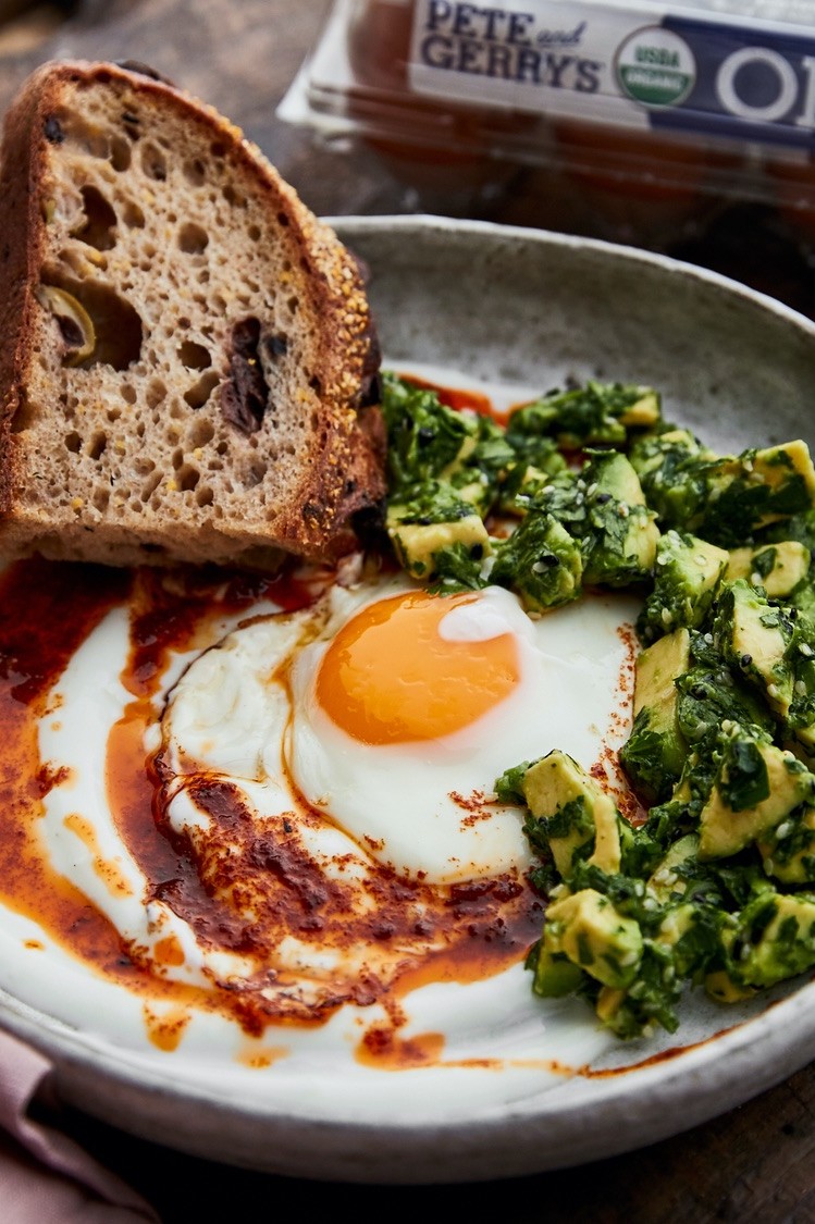 This Turkish eggs with harissa butter or "cilbir" is a great dish to add to the dinner lineup. Pictured is rustic bread served with a runny egg, a spoonful of avocado relish, and a drizzle of harissa butter. | peteandgerrys.com 