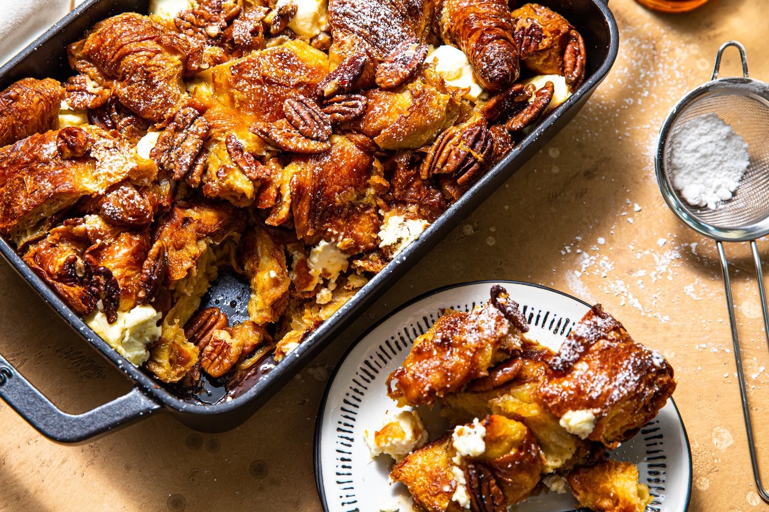 Maple pecan croissant French toast bake – a golden brown, nutty, sweet casserole-style breakfast dolloped with cream cheese and jam-packed with day-old butter croissants soaked in a cinnamon-cardamom-spiced custard batter.