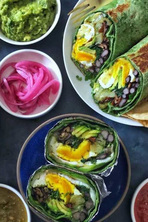 This green goddess breakfast burrito features spinach tortillas filled with collard greens, jack cheese, avocado, sweet potato, spinach, black beans, and organic eggs over easy. | peteandgerrys.com  