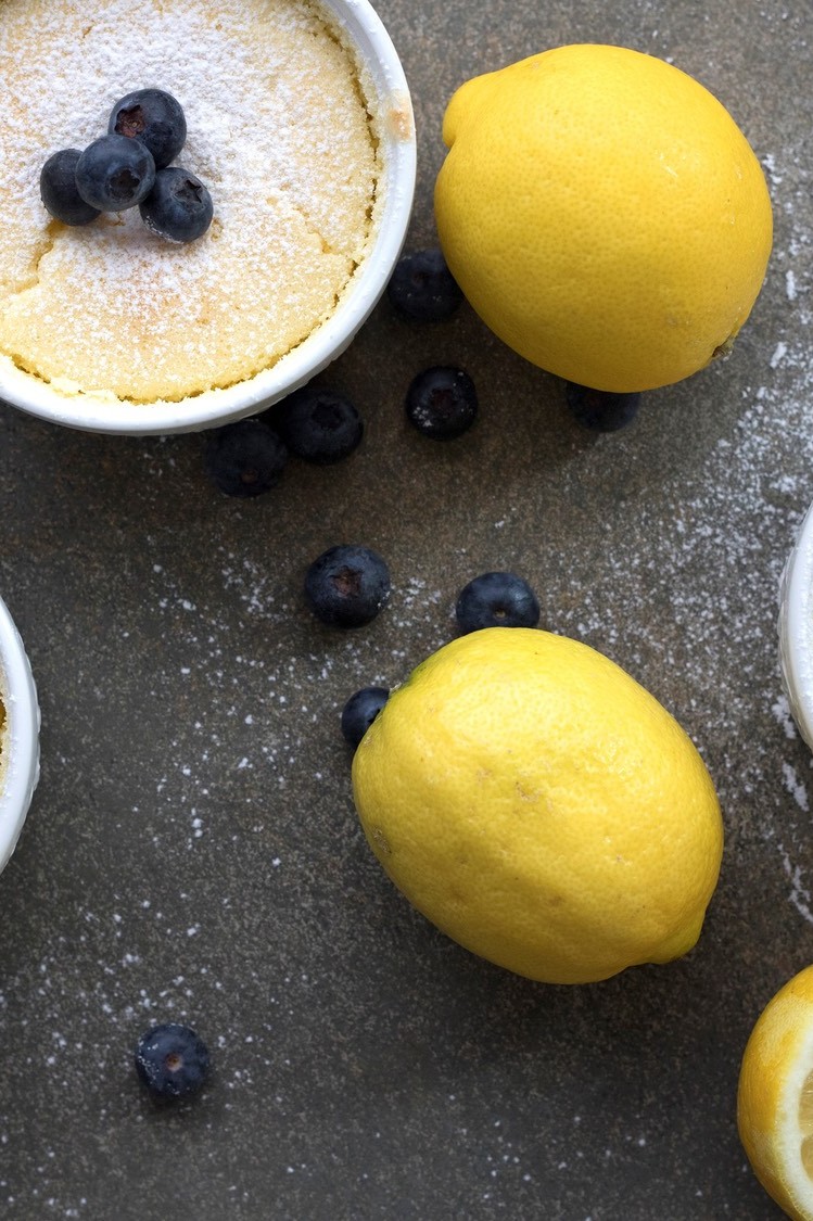 These keto-friendly lemon pudding cakes are pictured in individual ramekins. The cake is made of organic eggs, low-carb sweetener, almond flour, and fresh lemon juice. We topped our ramekins with powdered sugar and blueberries. | peteandgerrys.com 