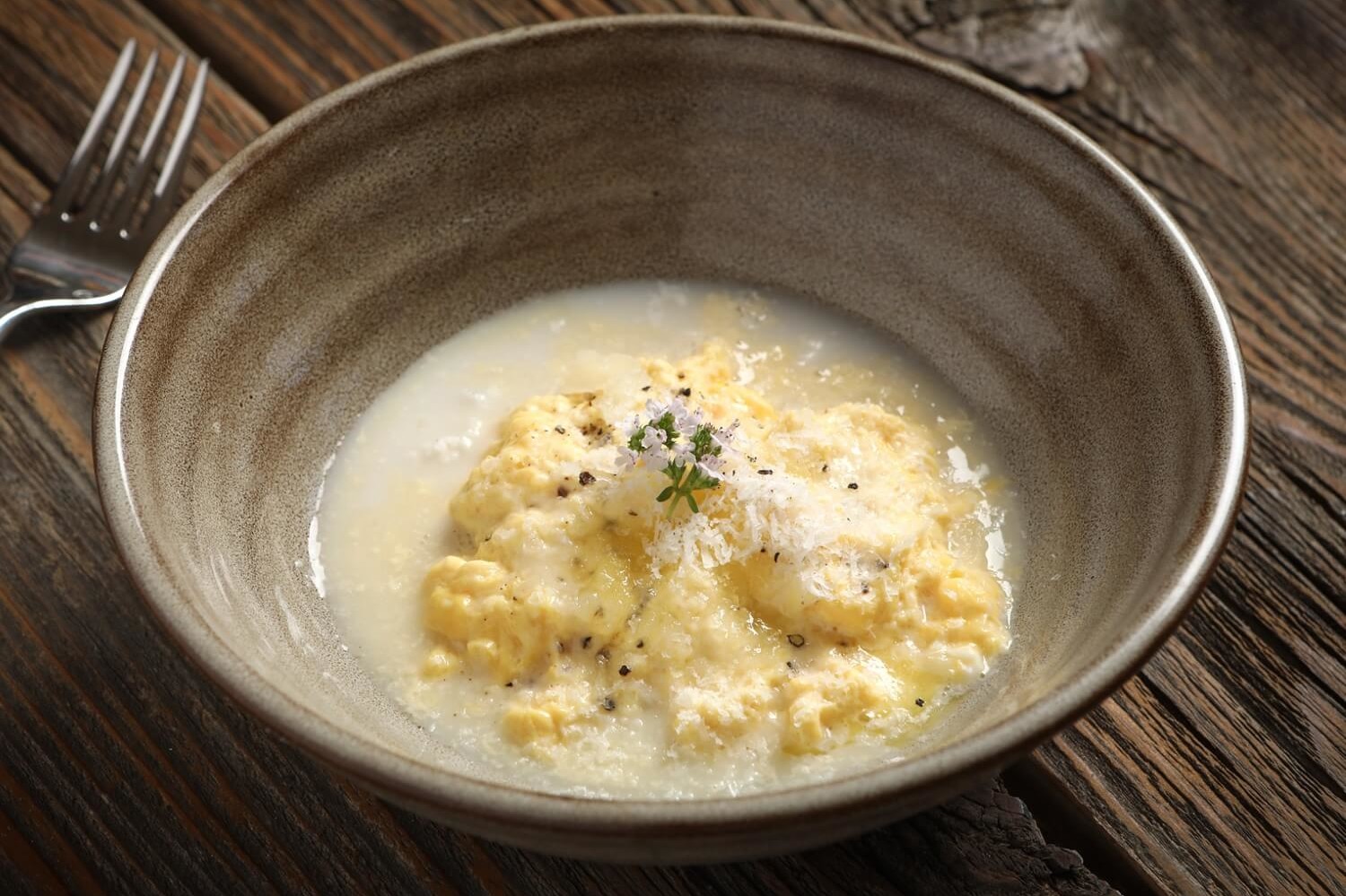 Delicately scrambled eggs poached in almond milk and butter. Served in a bowl with grated Manchego cheese and freshly ground black pepper. | peteandgerrys.com