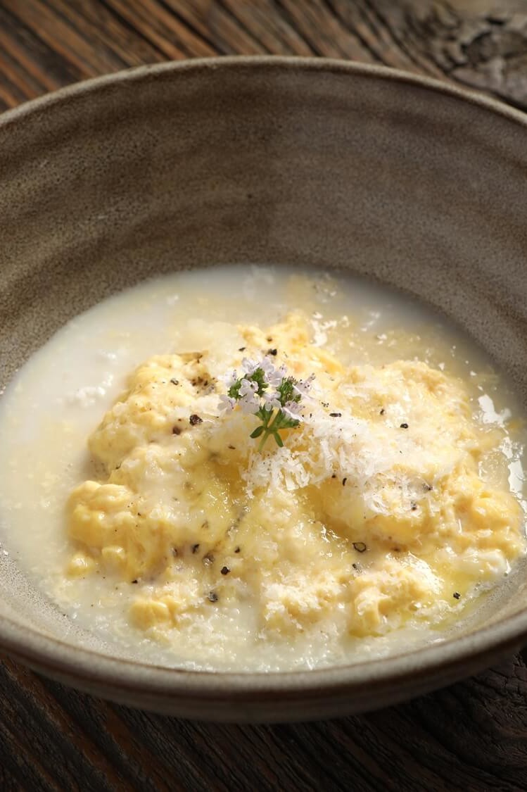 Delicately scrambled eggs poached in almond milk and butter. Served in a bowl with grated Manchego cheese and freshly ground black pepper. | peteandgerrys.com