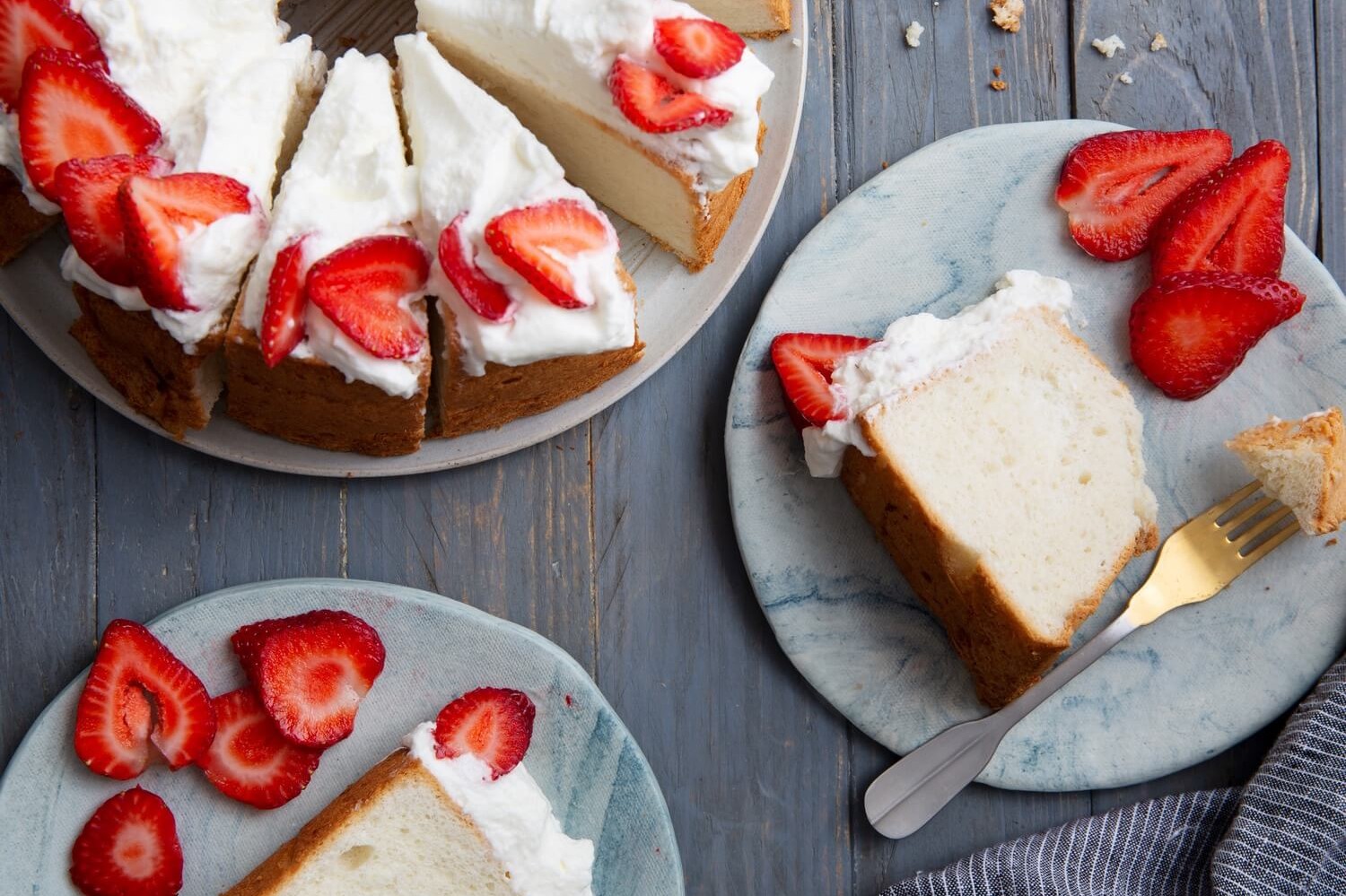 An airy, delightful angel food cake with a light crumb. Made with just seven ingredients and topped with whipped cream and fresh strawberries. | peteandgerrys.com 