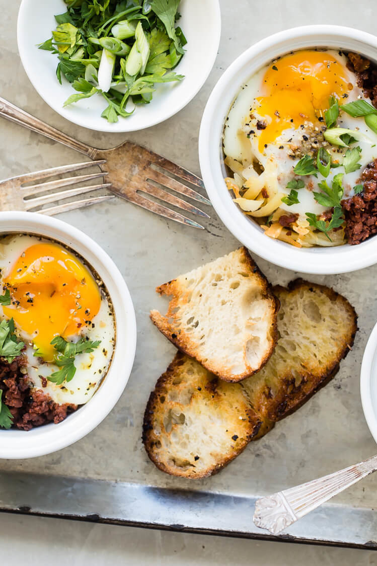 Organic eggs with runny yolks atop browned chorizo and hash browns. Each portion is baked in its own ramekin and served with toast on the side. | peteandgerrys.com