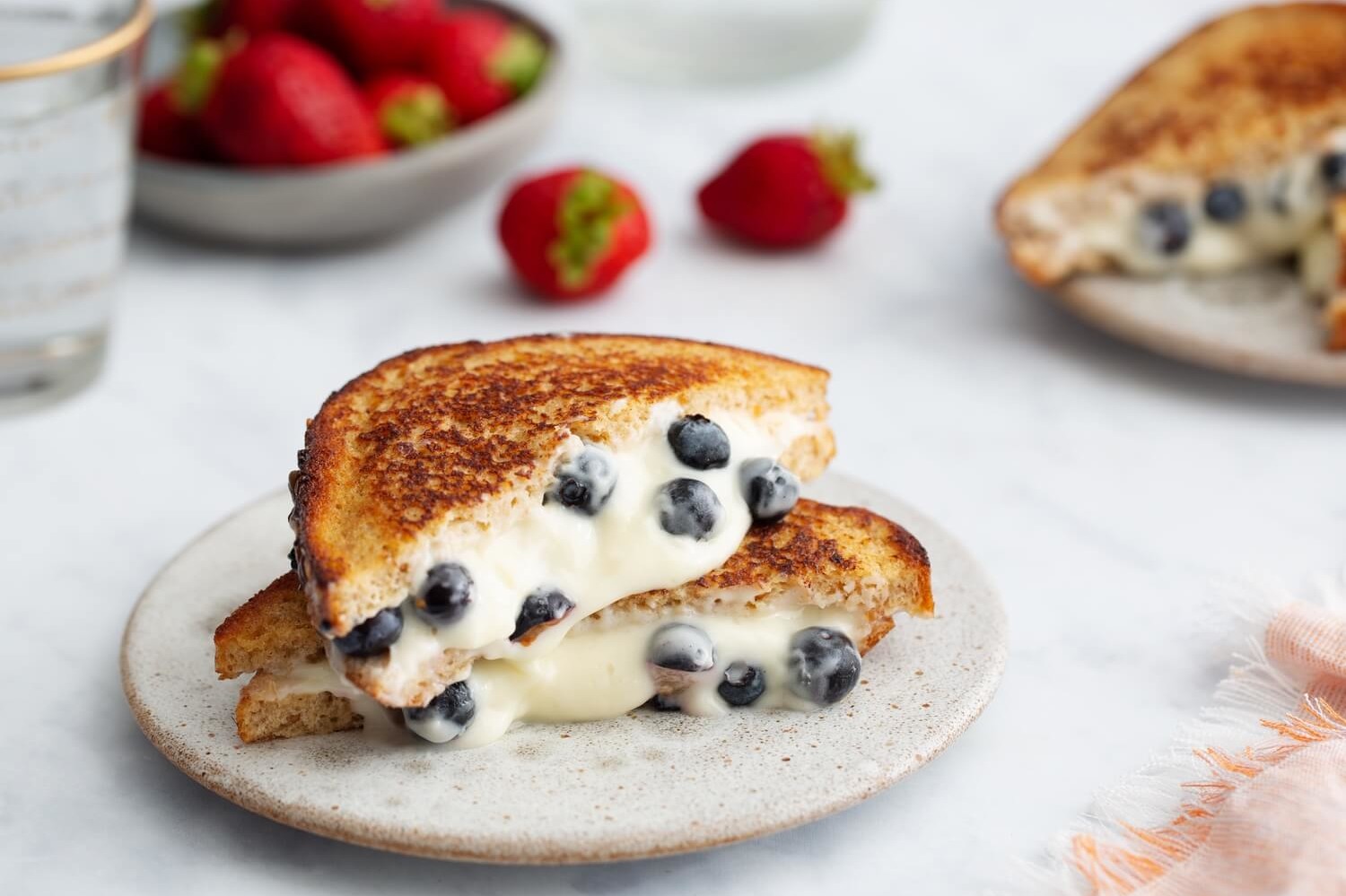 Blueberry French toast sandwich pan-fried until golden brown and cut in half. Cross section reveals that the French toast is stuffed with a sweet, melty blueberry and cream cheese filling. | peteandgerrys.com 