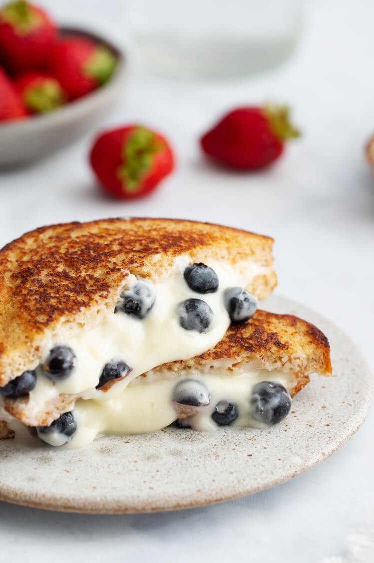 Blueberry French toast sandwich pan-fried until golden brown and cut in half. Cross section reveals that the French toast is stuffed with a sweet, melty blueberry and cream cheese filling. | peteandgerrys.com 