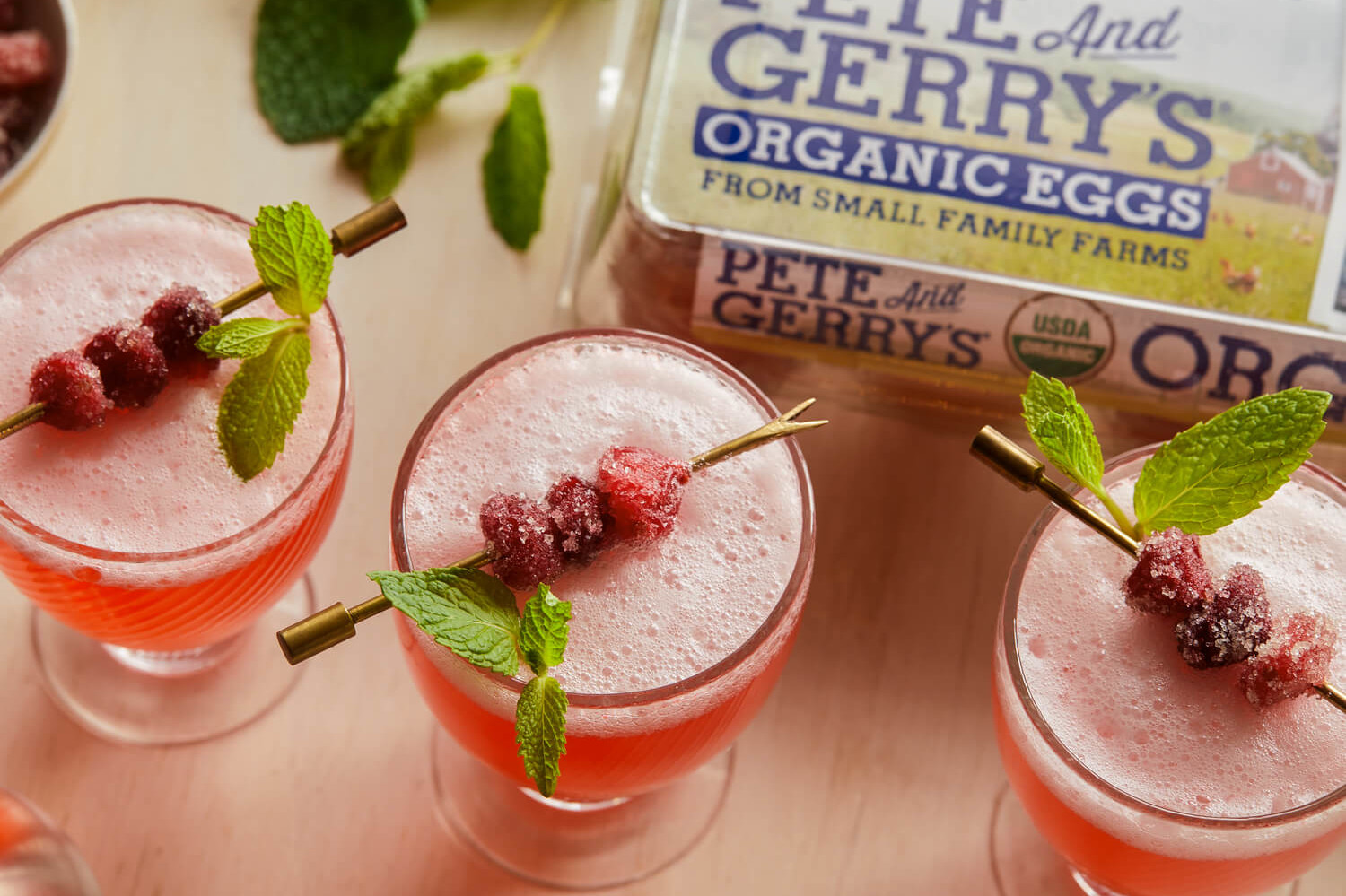 This fizzy cranberry mint punch cocktail is perfect for any season. Coupe glasses are filled with simple syrup, gin, fresh cranberries, and club soda. Topped with foamy egg whites and sugared cranberries. | peteandgerrys.com 