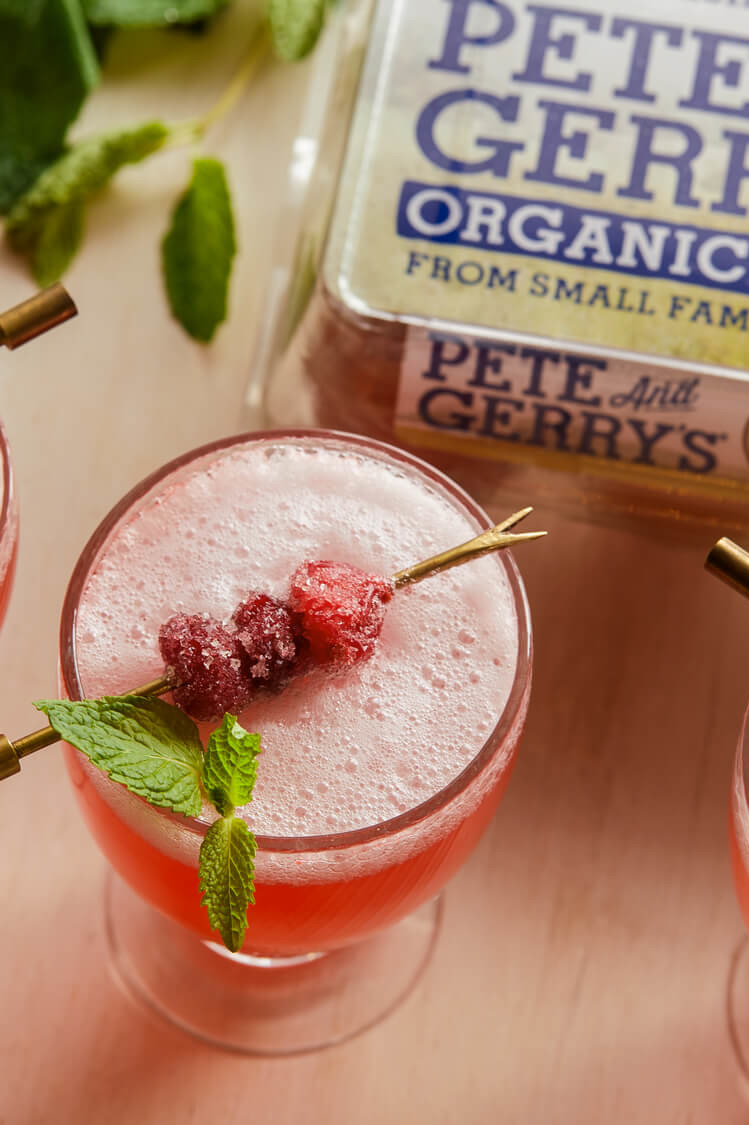 This fizzy cranberry mint punch cocktail is perfect for any season. Coupe glasses are filled with simple syrup, gin, fresh cranberries, and club soda. Topped with foamy egg whites and sugared cranberries. | peteandgerrys.com 