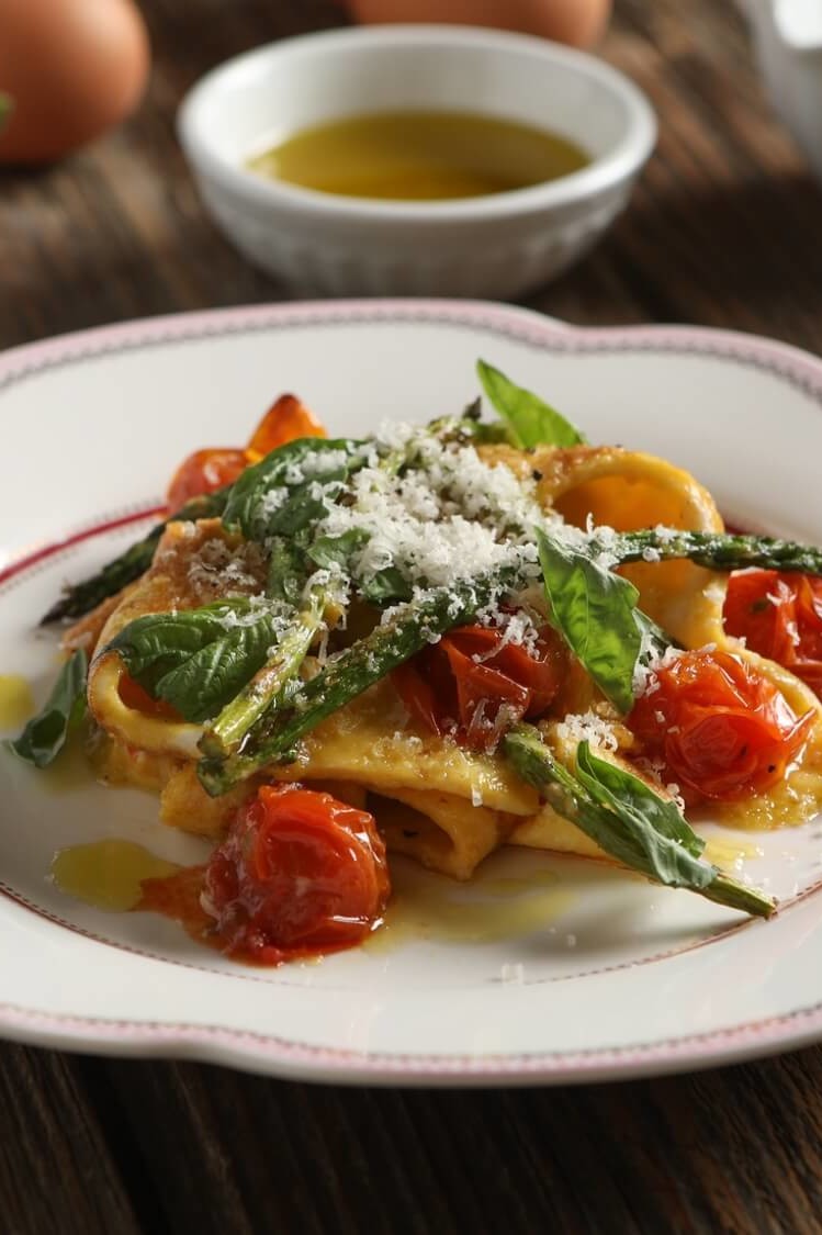 This gluten-free dish features homemade egg ribbon pasta, roasted asparagus, and blistered cherry tomatoes topped with Parmesan cheese. | peteandgerrys.com 