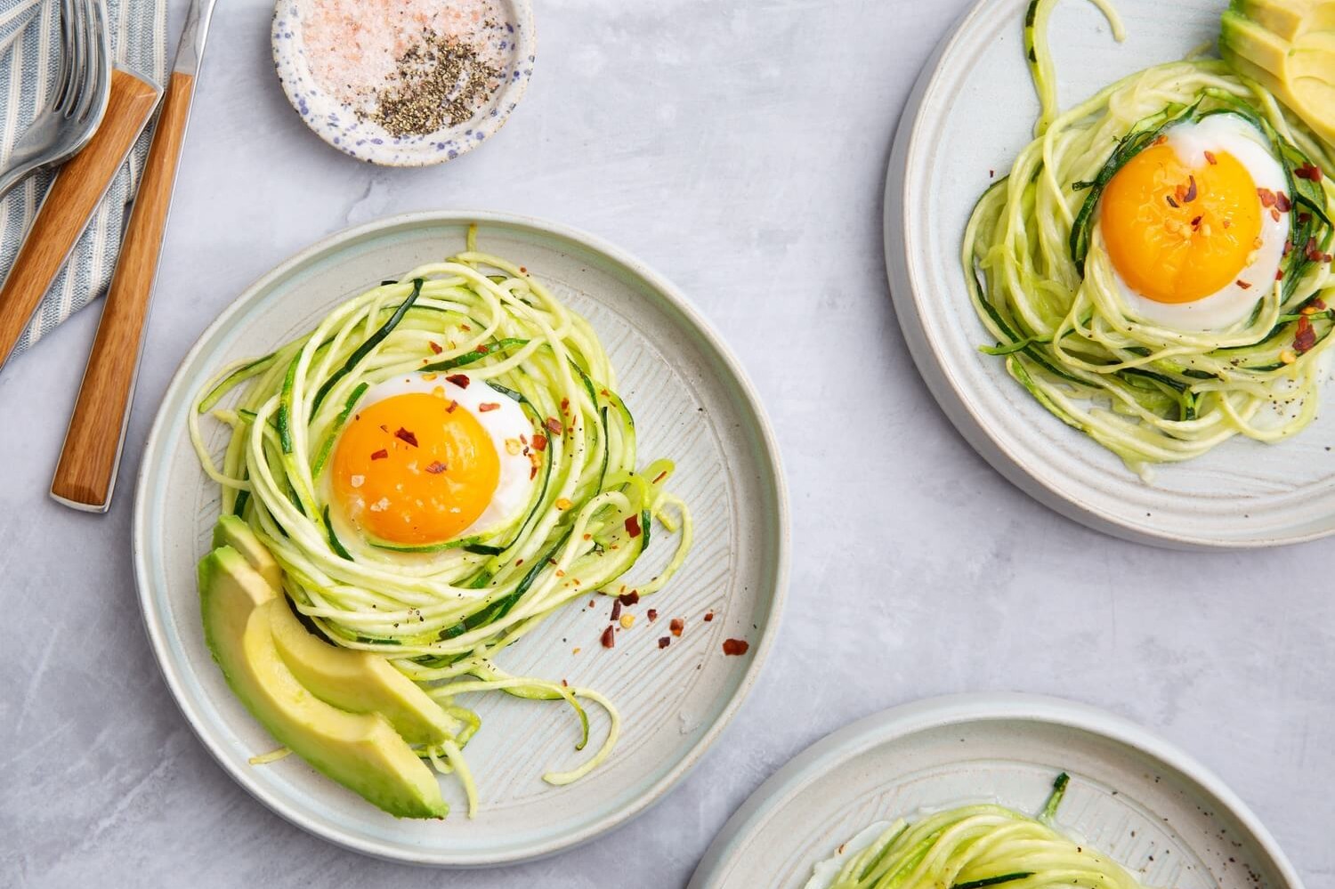 Low carb, keto-friendly eggs baked in zucchini noodle nests, also known as zoodles. Seasoned with red pepper flakes and serves with sliced avocado.| peteandgerrys.com 