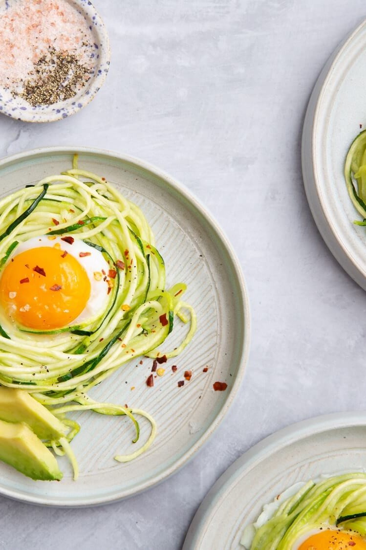 Low carb, keto-friendly eggs baked in zucchini noodle nests, also known as zoodles. Seasoned with red pepper flakes and serves with sliced avocado.| peteandgerrys.com 