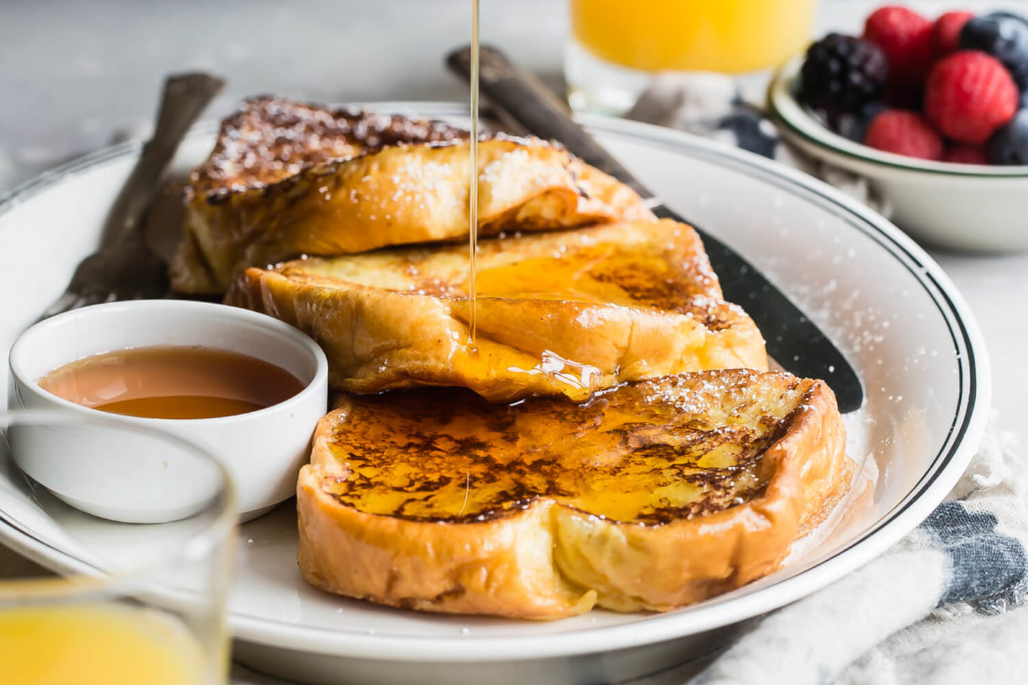 Golden brown eggnog French toast drizzled with maple syrup and dusted with powdered sugar. | peteandgerrys.com 