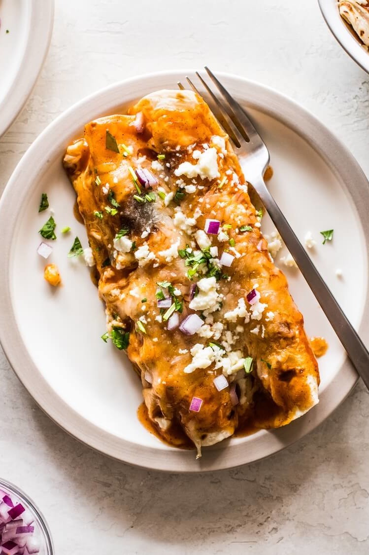 Breakfast enchiladas made with flour tortillas and stuffed with peppers, crumbled sausage, scrambled eggs, Southwest spices, and cheese. Topped with red enchilada sauce. | peteandgerrys.com 