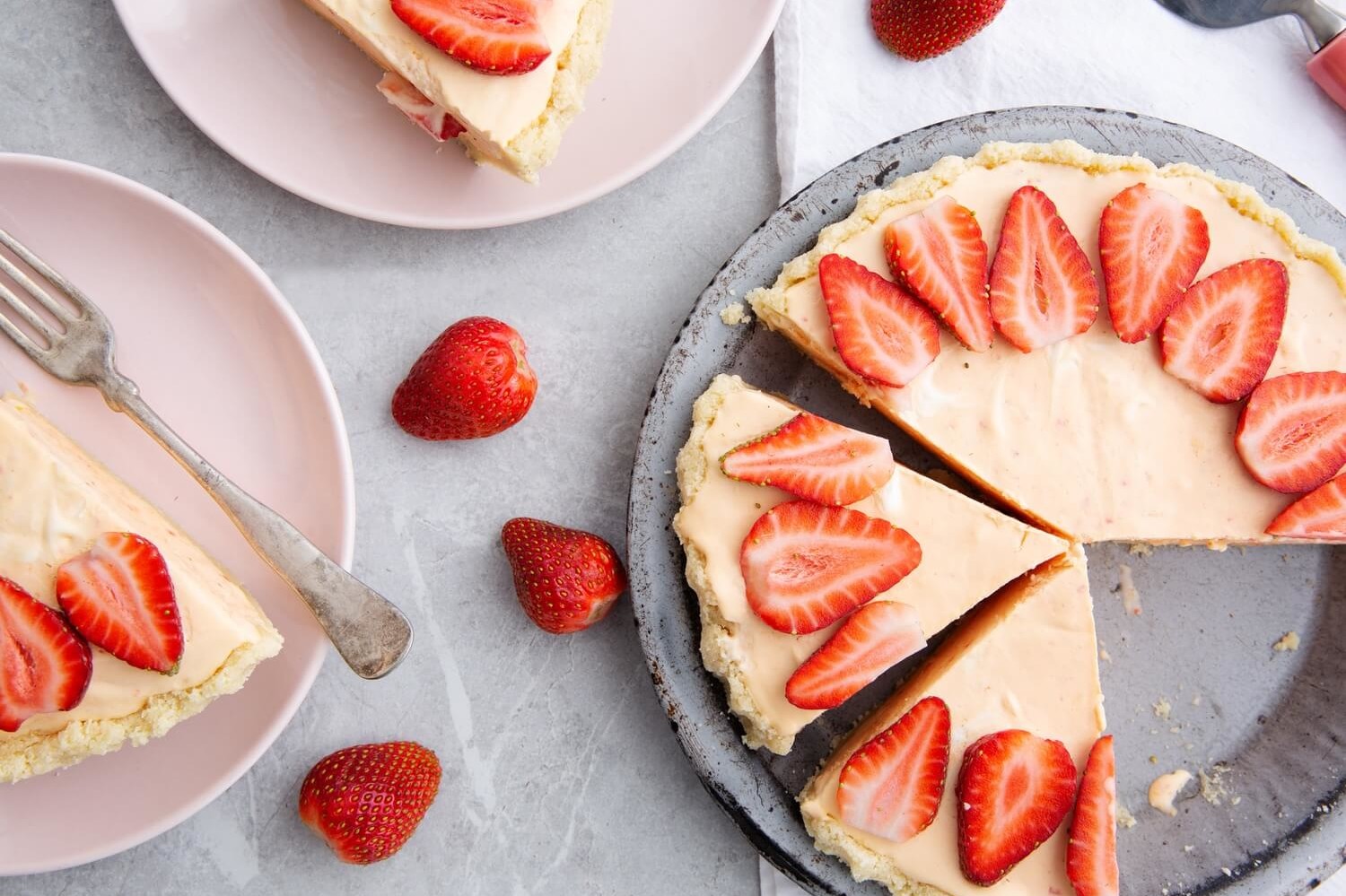 This keto-friendly frozen lemonade pie features an almond flour crust filled with a delicious blend of fresh lemon, sliced strawberries, and egg yolk custard. | peteandgerrys.com 