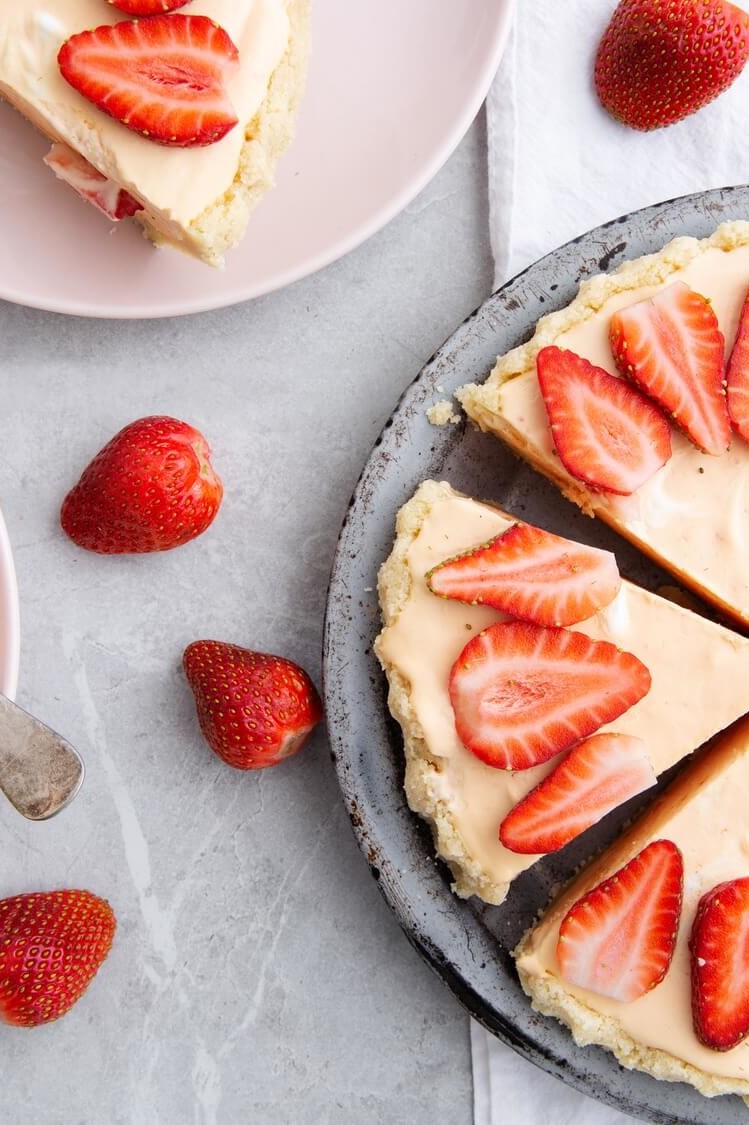 This keto-friendly frozen lemonade pie features an almond flour crust filled with a delicious blend of fresh lemon, sliced strawberries, and egg yolk custard. | peteandgerrys.com 