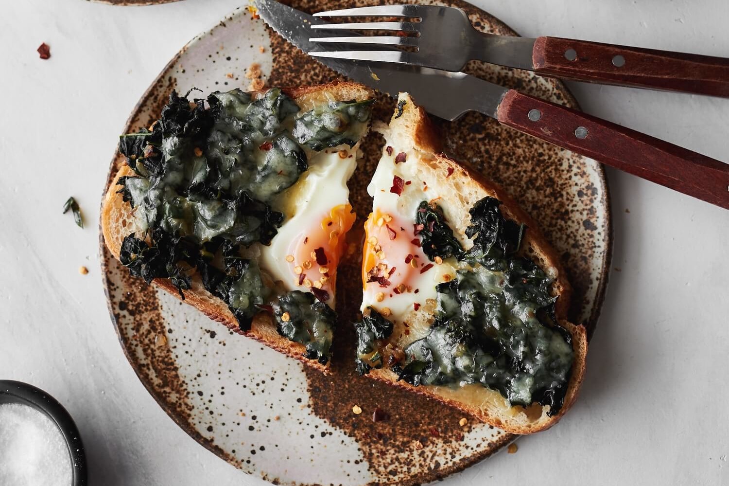 This kale egg in hole pictures toast with a runny organic egg in the middle. The egg is topped with a kale and fontina cheese mixture. | peteandgerrys.com 