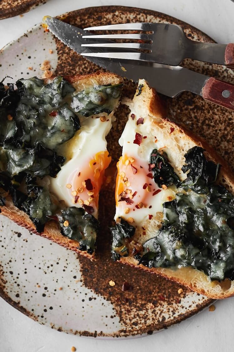 This kale egg in hole pictures toast with a runny organic egg in the middle. The egg is topped with a kale and fontina cheese mixture. | peteandgerrys.com 