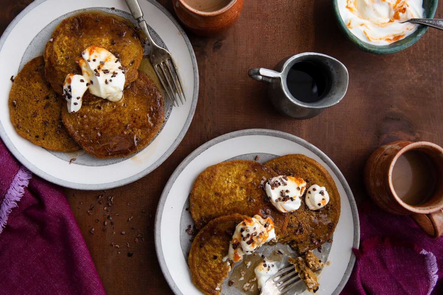 These gluten-free oatmeal pumpkin pancakes are perfect for autumn. These pancakes are beautiful orange-brown. The pancakes are served with whipped butter and cocoa nibs. | peteandgerrys.com 