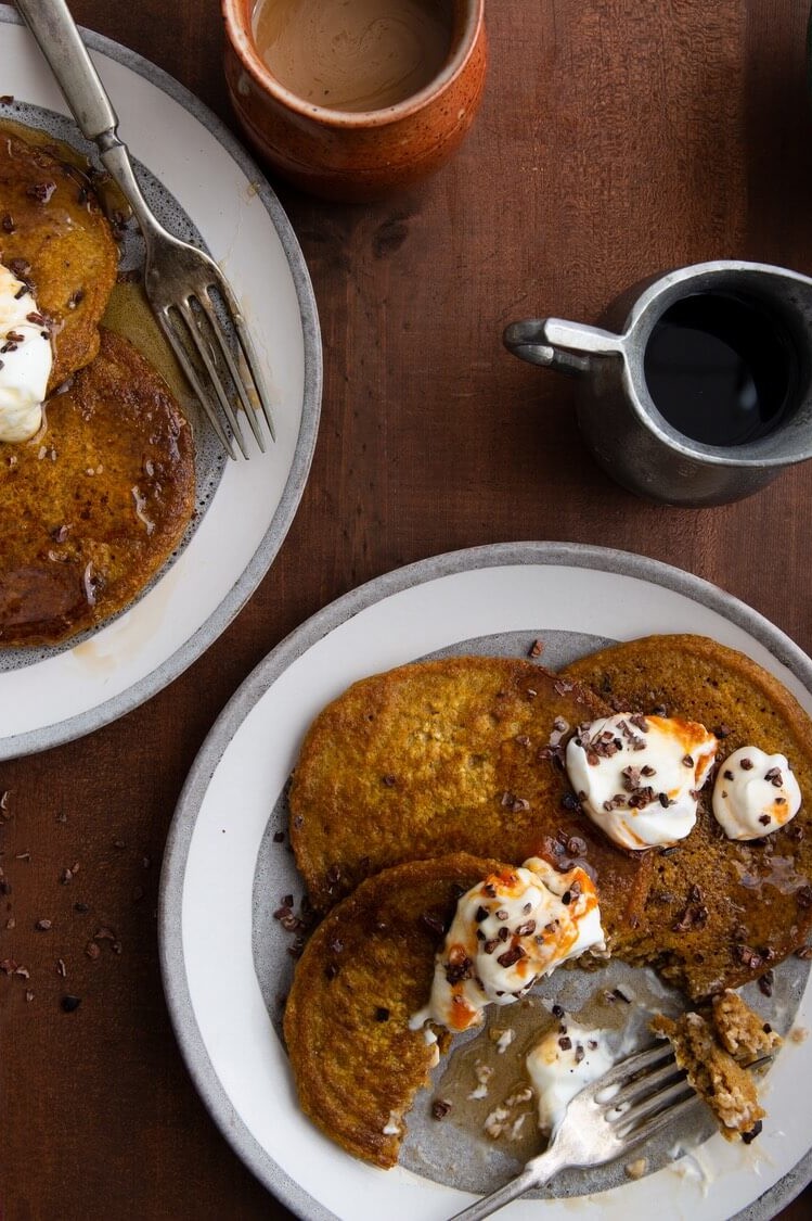 These gluten-free oatmeal pumpkin pancakes are perfect for autumn. These pancakes are beautiful orange-brown. The pancakes are served with whipped butter and cocoa nibs. | peteandgerrys.com 