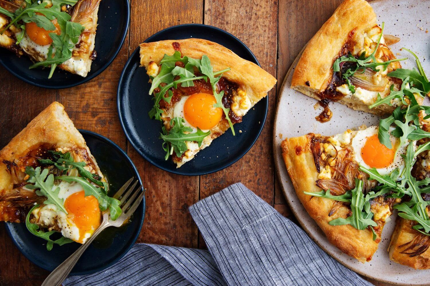 This good morning pizza features whole wheat dough, shallots, goat cheese, fig preserves, and arugula. Topped with a runny organic egg. | peteandgerrys.com 