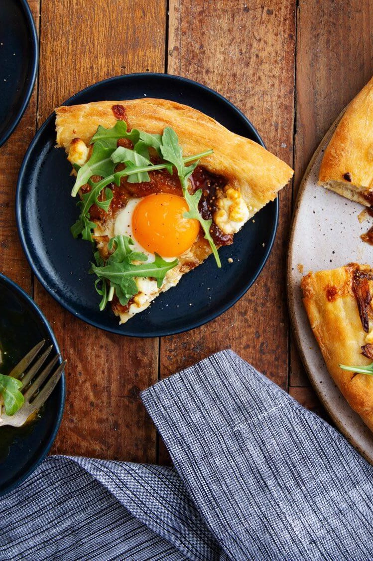 This good morning pizza features whole wheat dough, shallots, goat cheese, fig preserves, and arugula. Topped with a runny organic egg. | peteandgerrys.com 