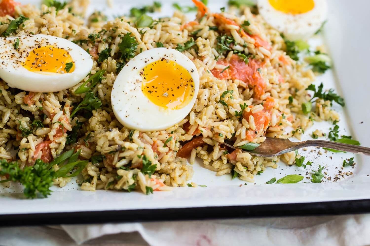 This kedgeree pictures cooked basmati rice, smoked salmon, and soft boiled organic eggs. This dish is garnished with fresh parsley. | peteandgerrys.com 