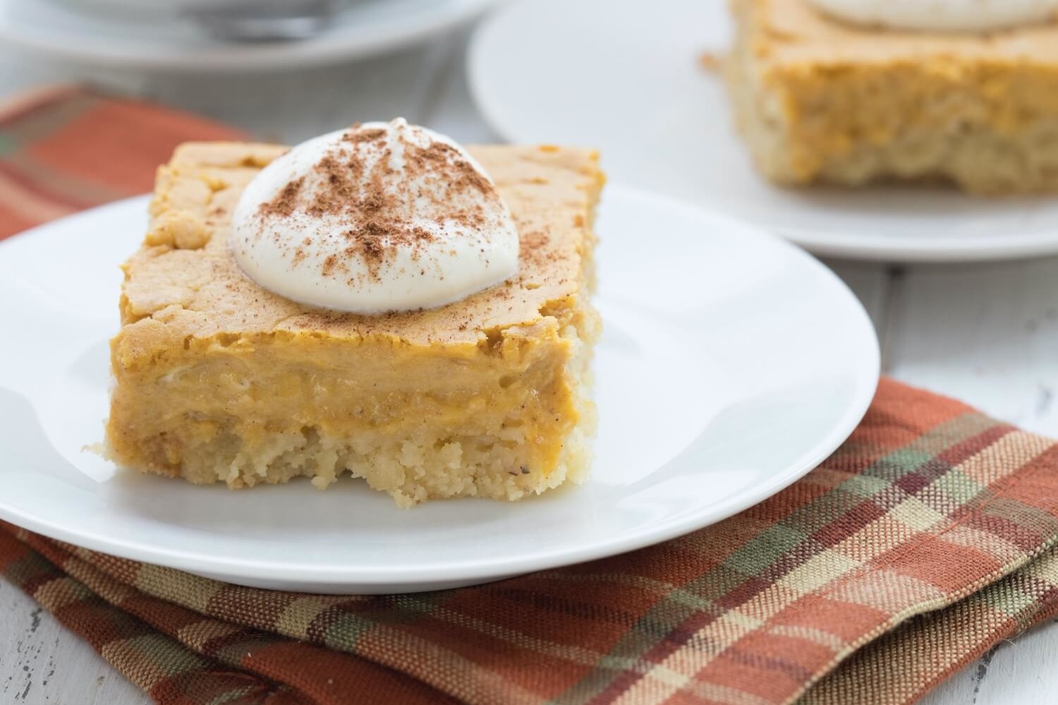 This keto pumpkin gooey butter cake is made with almond flour, organic eggs, cream cheese, and pumpkin puree. Pictured is the layered cake with the top layer very gooey from the bottom layers. | peteandgerrys.com