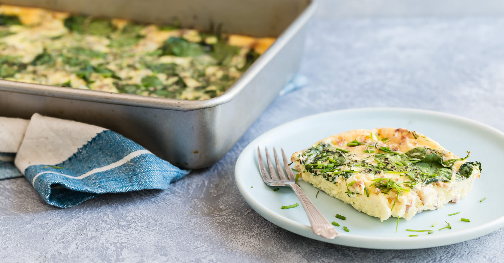 A keto-friendly crustless quiche made in a rectangular casserole pan. Quiche consists of organic eggs, heavy cream, white cheddar cheese, bacon, chives, scallions, and spinach. | peteandgerrys.com 