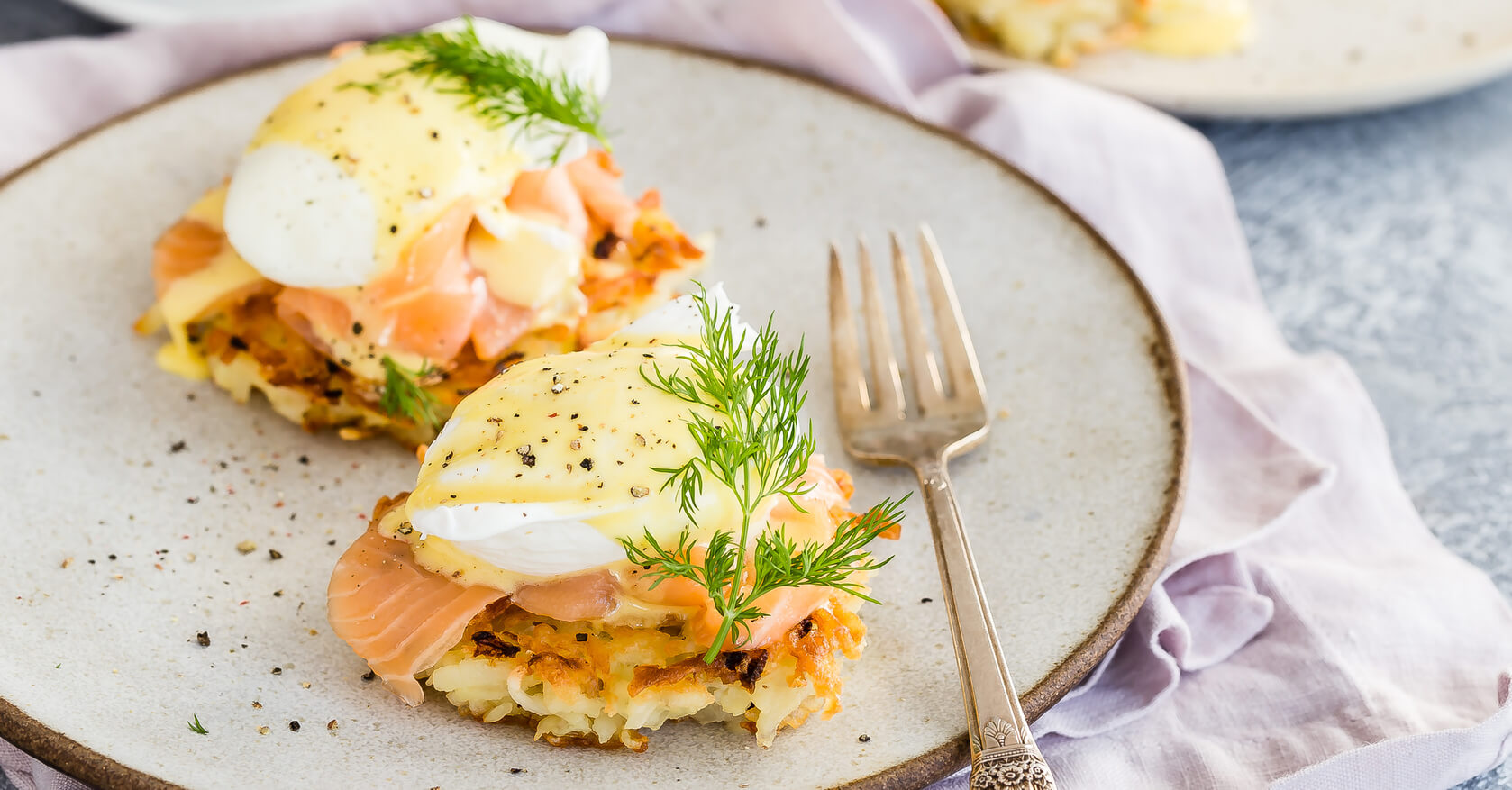 Eggs benedict on crispy, golden, latkes. Organic eggs are poached and covered with a creamy hollandaise sauce. Plated on smoked salmon, dill, and latkes. | peteandgerrys.com 