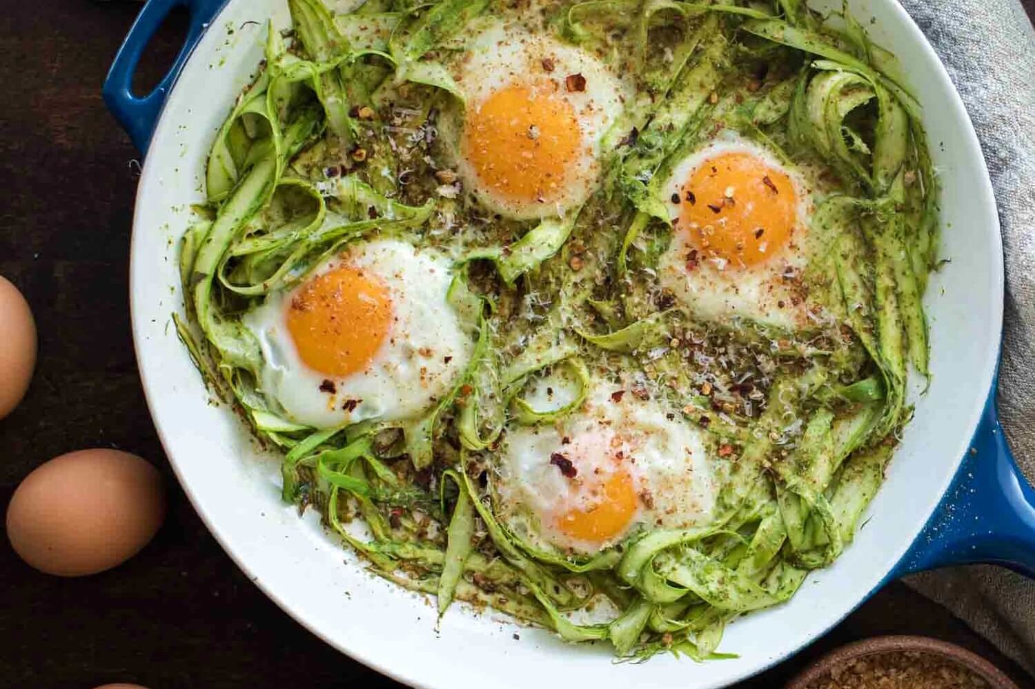 This pesto asparagus egg skillet is praised by vegetarians and meatless-Monday practicers alike. This recipe features shaved asparagus noodles, olive oil, pesto, bread crumbs, parmesan cheese, and organic baked eggs. | peteandgerrys.com 