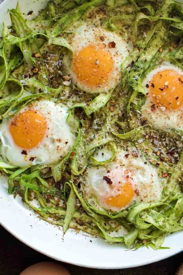 This pesto asparagus egg skillet is praised by vegetarians and meatless-Monday practicers alike. This recipe features shaved asparagus noodles, olive oil, pesto, bread crumbs, parmesan cheese, and organic baked eggs. | peteandgerrys.com 