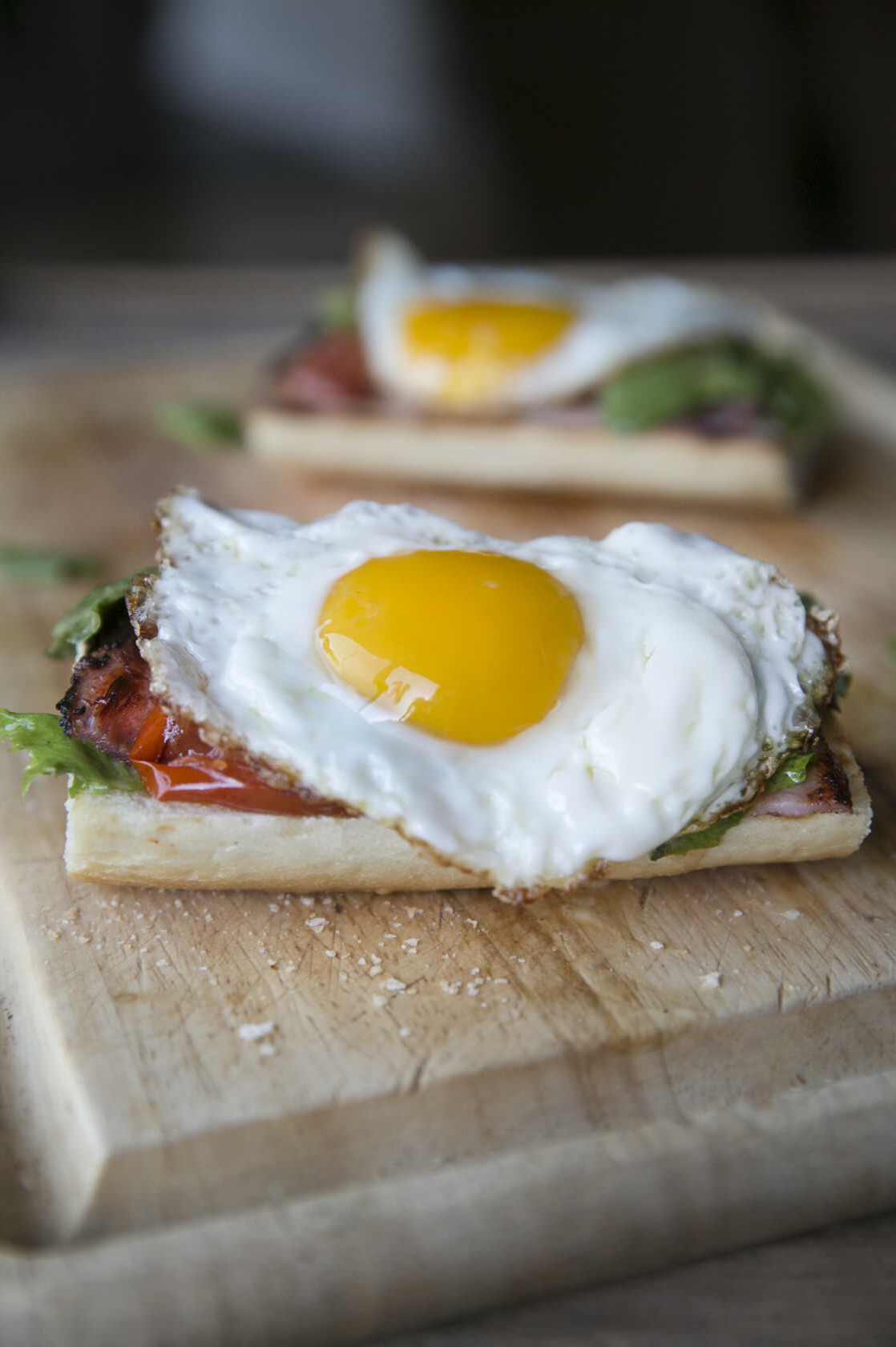 This open-faced egg sandwich features a fried egg on top of thick-sliced tomatoes, greens, and crusty french bread. | peteandgerrys.com 