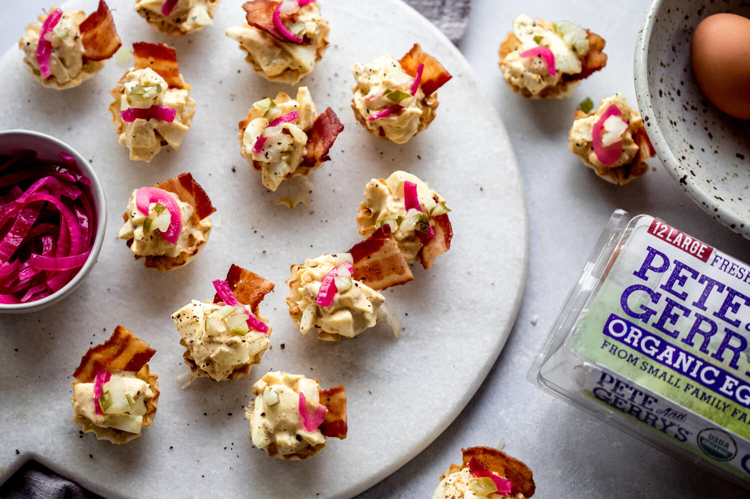 Party-ready phyllo egg salad bites adorned with crispy bacon and homemade pickled red onion. | peteandgerrys.com 