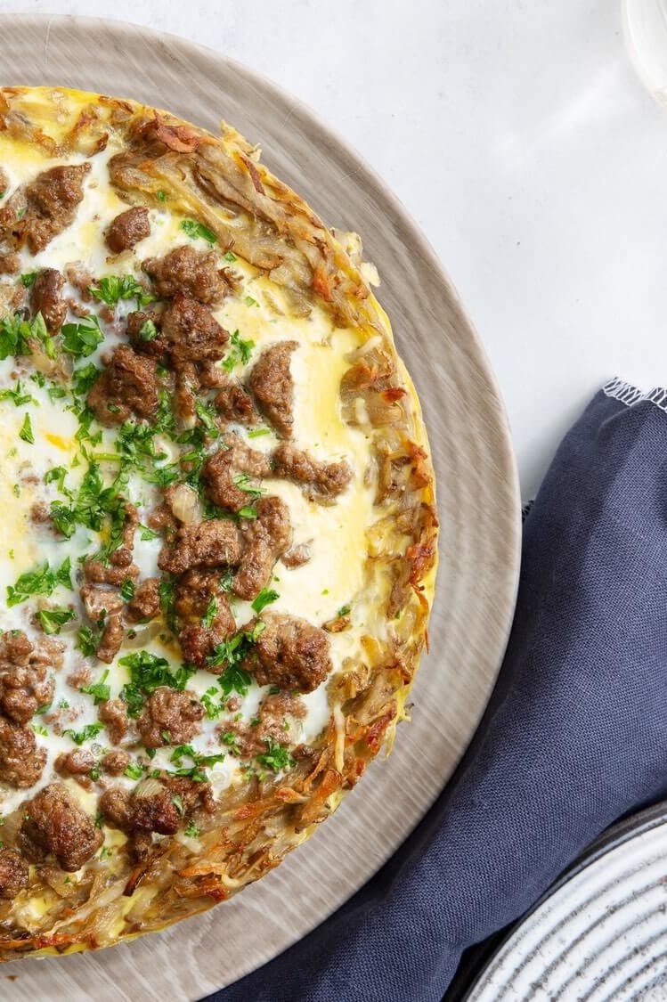 This potato quiche is cooked with an organic egg filling until golden brown. Pictured on top of the quiche are crumbled ground beef, shredded cheese, and parsley. | peteandgerrys.com 