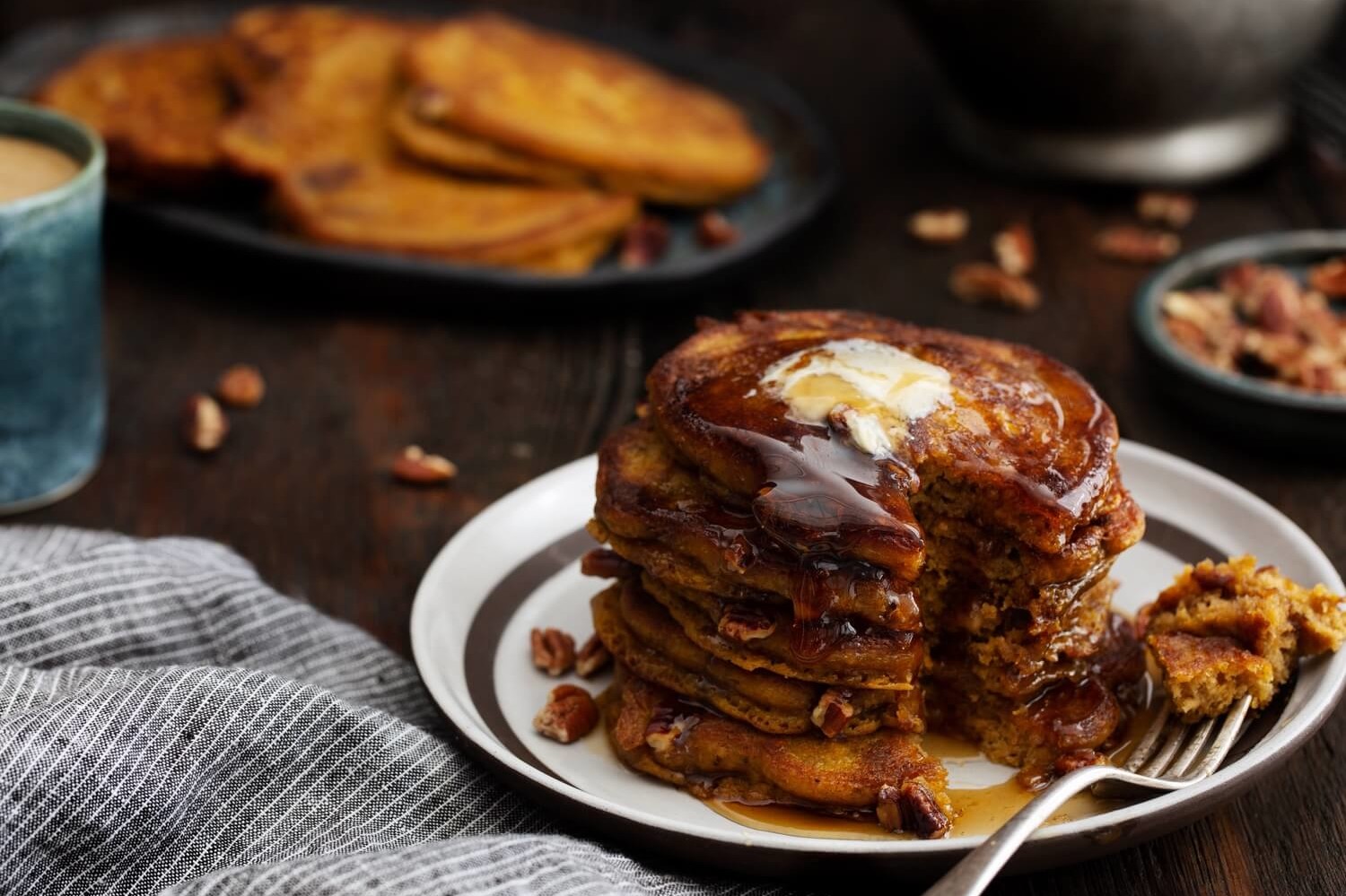 These pumpkin pecan pancakes are moist on the inside and cooked until golden on the outside. Pictured is maple syrup and Nellie's butter in the top cross-section. | peteandgerrys.com 