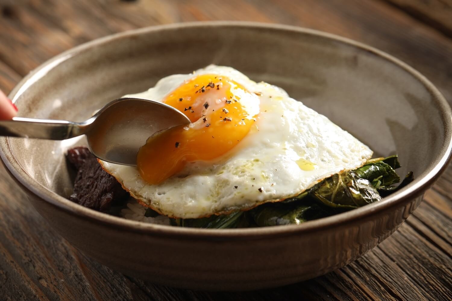 A beef, rice, and egg bowl created by Chef Edward Lee. Flat iron steak is marinated with soy sauce, garlic, and ginger, then seared and served with greens and white rice. Dish is topped with a runny fried egg. | peteandgerrys.com 