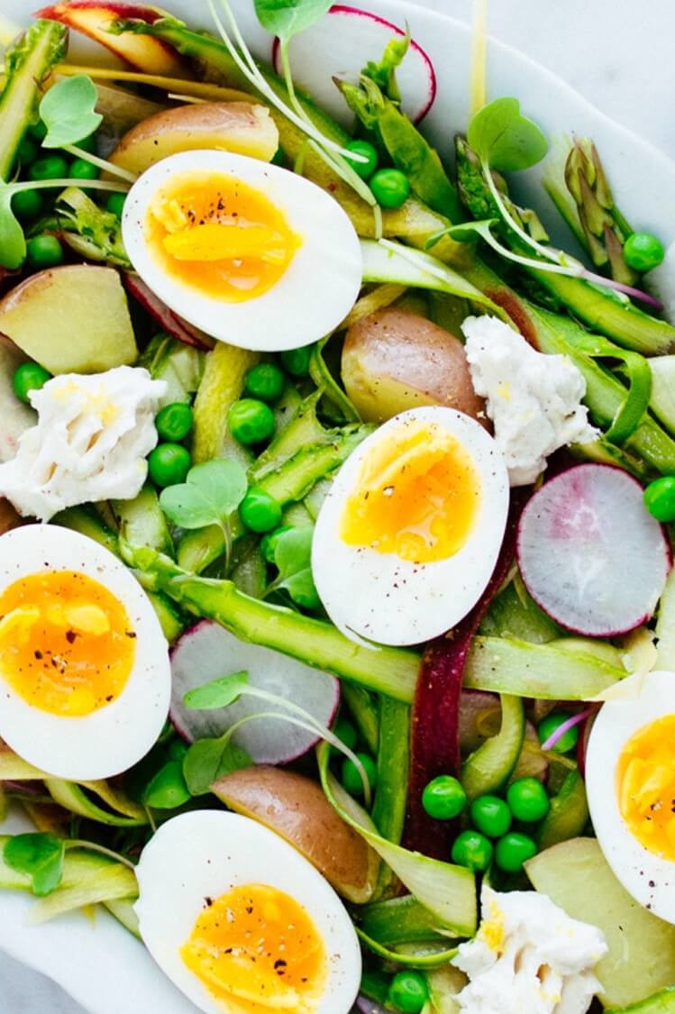 This shaved asparagus salad is light and refreshing. Pictured is bright green asparagus, sweet peas, radishes, goat cheese, and soft boiled eggs. | peteandgerrys.com 