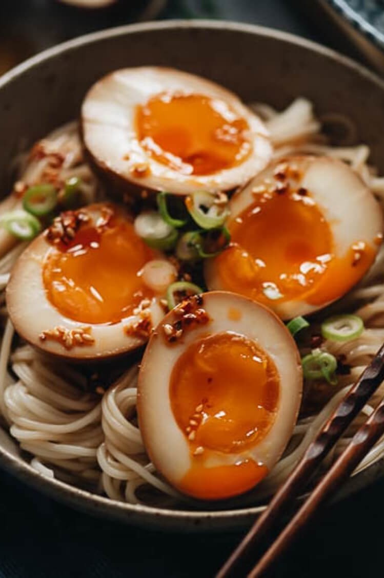 Soy sauce and Asian flavored soft boiled organic eggs, sit atop of ramen noodles, and rice. This dish is topped with scallions. | peteandgerrys.com 