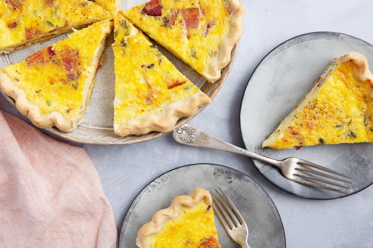 Pictured is a bright yellow swiss onion quiche with pieces of bacon and fresh thyme. This recipe features homemade crust and organic eggs. | peteandgerrys.com 