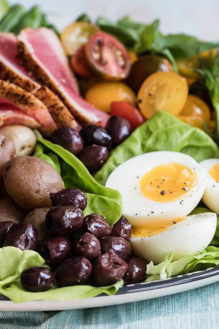 This colorful Niçoise salad features mixed greens, sliced ahi tuna, jammy soft-boiled eggs, olives, and a variety of other mix-ins. Served with a light white wine vinaigrette. | peteandgerrys.com  