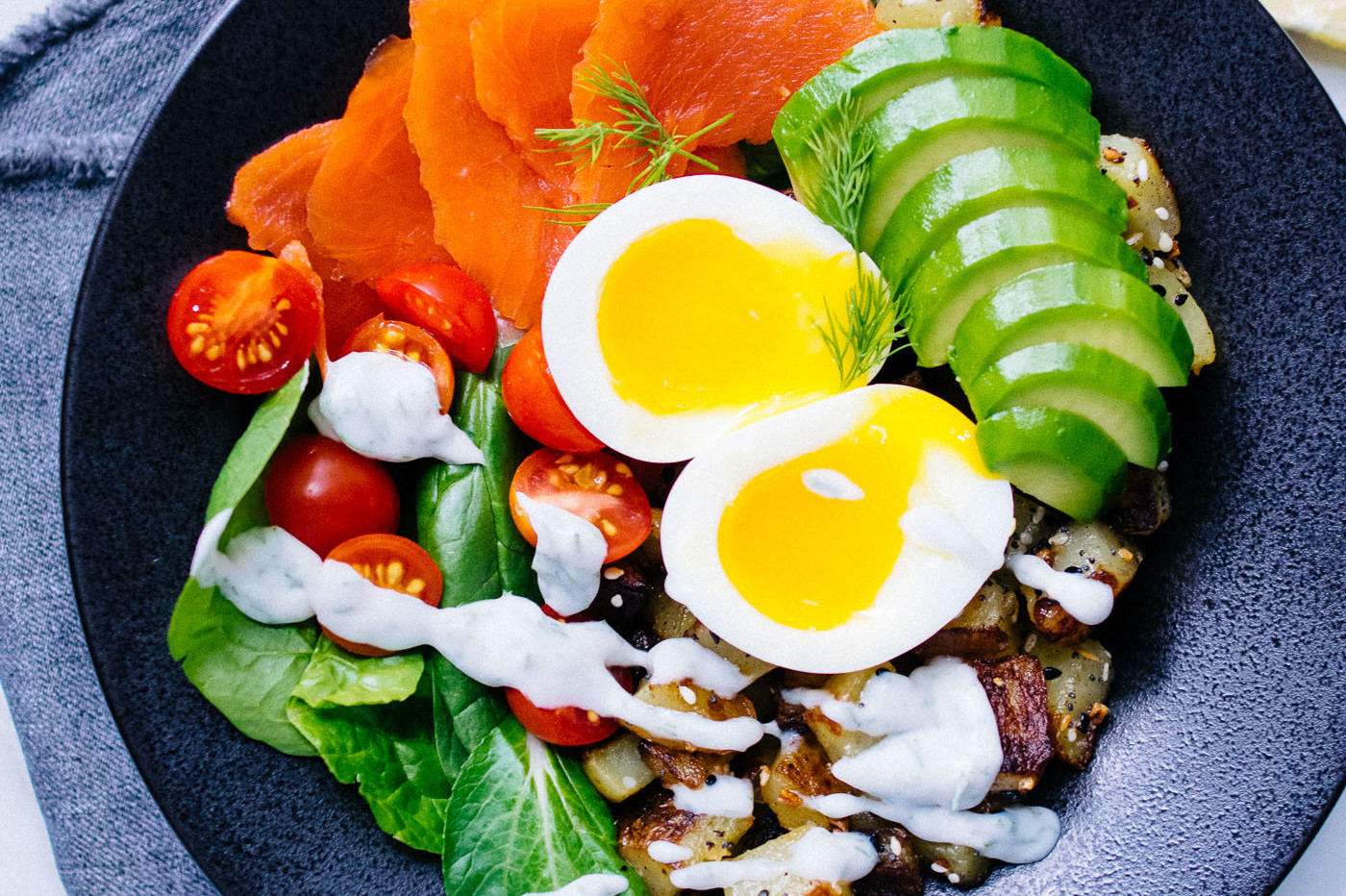 This soft boiled egg and smoked salmon bowl is a perfect healthy lunch. At the center of the picture, there's runny soft boiled organic eggs, cucumber slices, spinach, and salmon. | peteandgerrys.com 