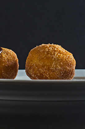 Baharat-spiced sufganiyot, or round Hanukkah donuts originating in Israel. Donuts are fried until golden brown and rolled in a mix of cinnamon, sugar, and other warming spices. Plated and drizzled with melted chocolate. | peteandgerrys.com 