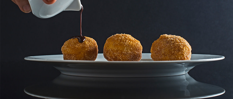 Baharat-spiced sufganiyot, or round Hanukkah donuts originating in Israel. Donuts are fried until golden brown and rolled in a mix of cinnamon, sugar, and other warming spices. Plated and drizzled with melted chocolate. | peteandgerrys.com 